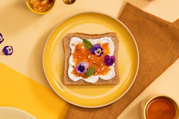 Une tranche de pain de mie Bio complet sur lequel il y a 4 pêches bien mûres 1 cuillère à soupe de fromage blanc 1 poignée d’amandes effilées Quelques fleurs de Pensée